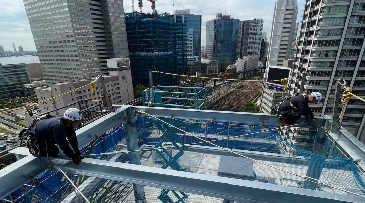 高層ビルの鉄骨上で作業する株式会社吉田鉄建の職人